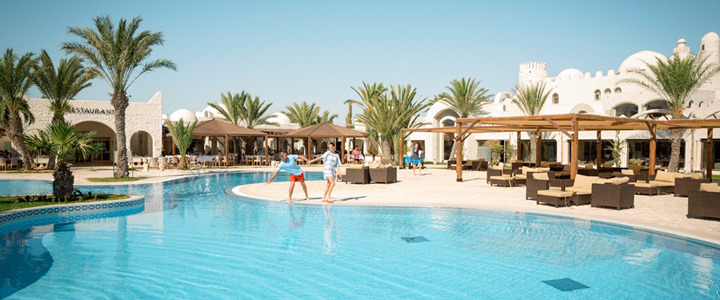 landingpage_TUID_Galerie_01_20251006 ROBINSON DJERBA BAHIYA: Auf Djerba in Tunesien – Paar genießt den türkisblauen Pool vor der Hotelkulisse.