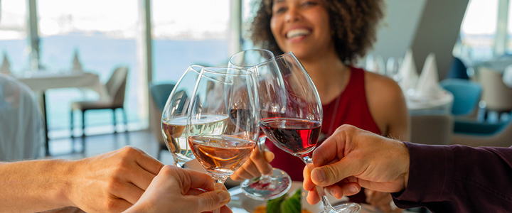 Genießen Sie die Zeit auf der MS Relax in einem der zahlreichen Restaurants. Junge Menschen stoßen mit Wein an.