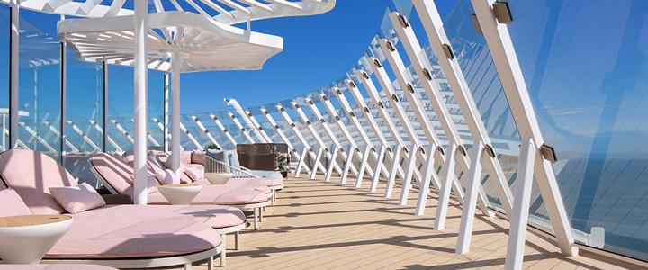 Pastellrosa Sonnenliegen im Vordergrund; Blick auf das Meer.