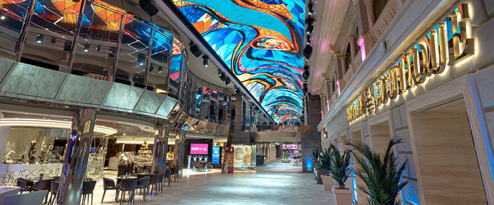 MSC Euribia: Innenraum des Kreuzfahrtschiffes mit Blick auf ein Bordrestaurant und einen weiten Gang; farbenfrohe, gemusterte Decke.