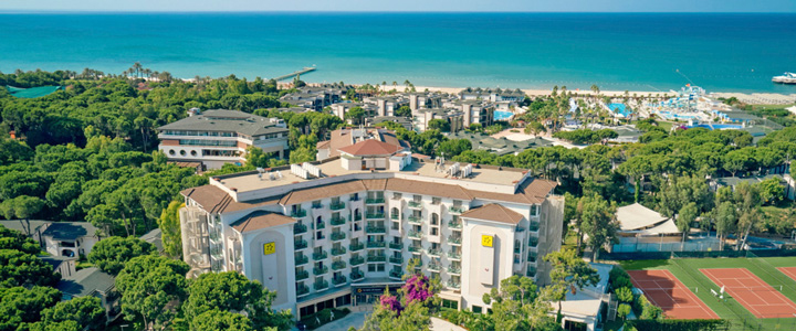 TUI MAGIC LIFE Masmavi Hotel in Belek, eingebettet in viel Grün, mit Strand und türkisfarbenem Meer im Hintergrund.