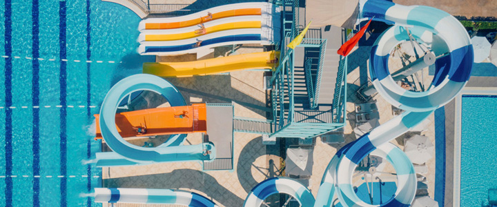Blick von oben auf farbenfroh gestaltete Wasserrutschen in Blau- und Gelbtönen.