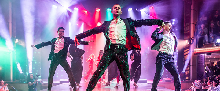 Tänzer im Pinken Spotlight auf der Bühne bei einer der glänzenden Abendshows auf der AIDAnova.