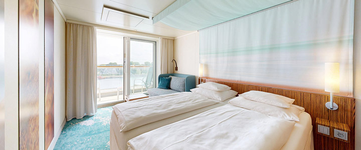 Blick durch eine Außenkabine der AIDAdiva, vorbei am Doppelbett nach draußen auf den eigenen Balkon.