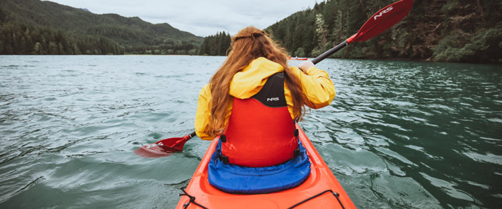Frau beim Paddeln im Kanu in der ursprünglischen Natur von Alaska.