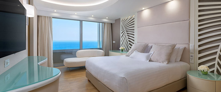 Helles Schlafzimmer im Rodos Palace mit Doppelbett in offener, freundlicher Gestaltung und weitem Blick über das Meer.