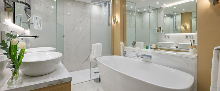 Stilvolles, exklusives Badezimmer im Rodos Palace mit viel Glas, heller Beleuchtung und großer Badewanne in eleganter Atmosphäre.