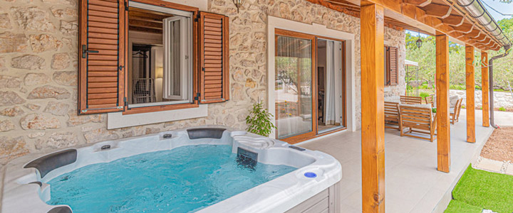 Ein türkiser, sprudelnder Whirlpool lädt auf der Terrasse eines typisch steinernen Ferienhauses in Kroatien zum Verweilen ein.