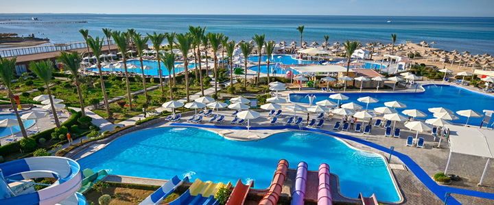 Die weitläufige Poollandschaft des SUNRISE Azalea Aqua Park Resort mit Wasserrutschen und Palmen reicht bis zum Strand und türkisblauen Meer.