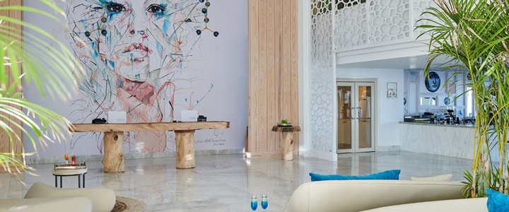 Der helle Innenbereich des Steigenberger Pure Lifestyle verbindet warmes Holz mit moderner Kunst. Ein großformatiges Frauenporträt prägt die Wand.
